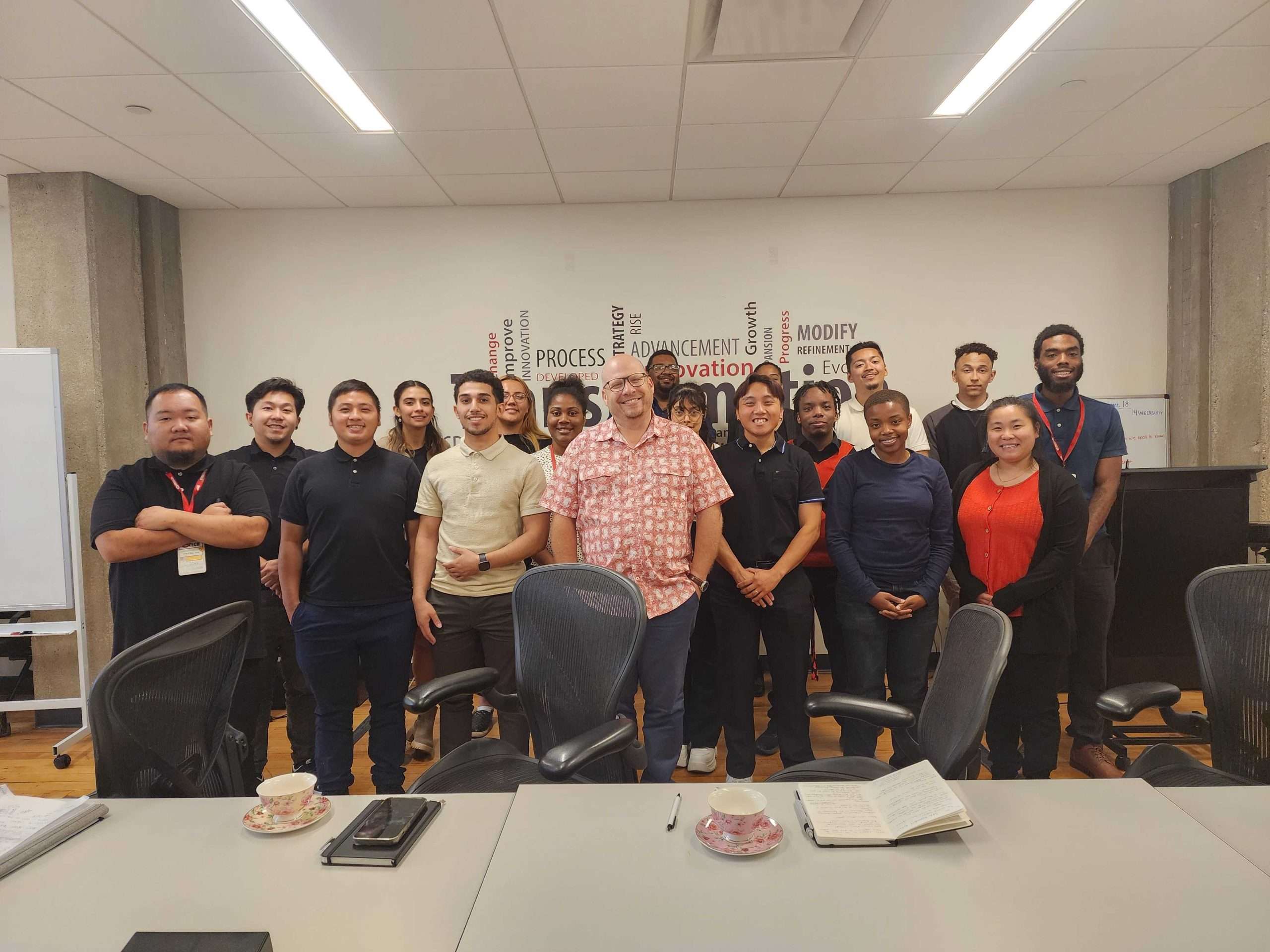 Group photo of i.c.stars Cycle 13 participants and Sam Hilgendorf, CIO of Fox World Travel, standing together in a conference room.