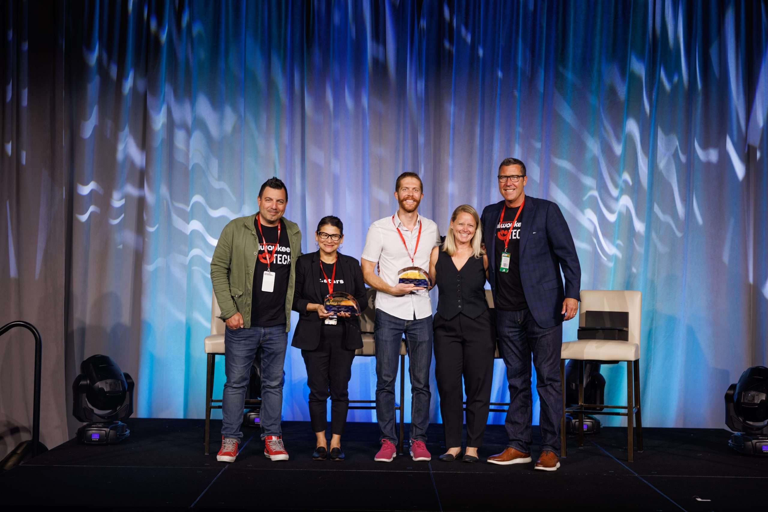 Group of leaders on stage at Summerfest Tech event, smiling after a recognition moment.